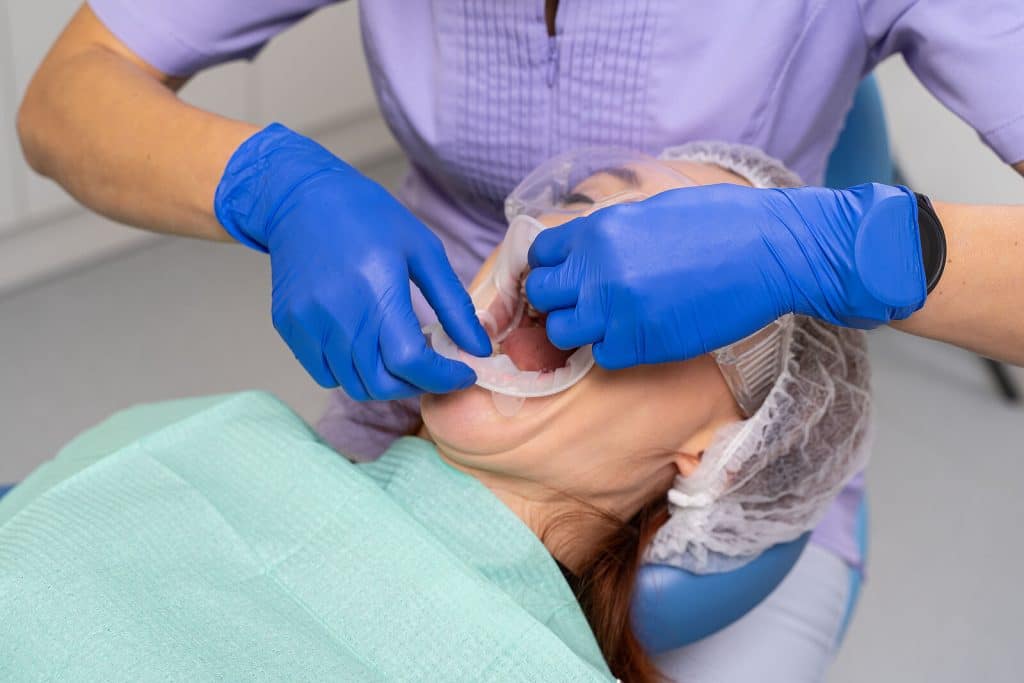 The dentist putting dental dam in the patient's mouth|The dentist putting dental dam in the patient's mouth