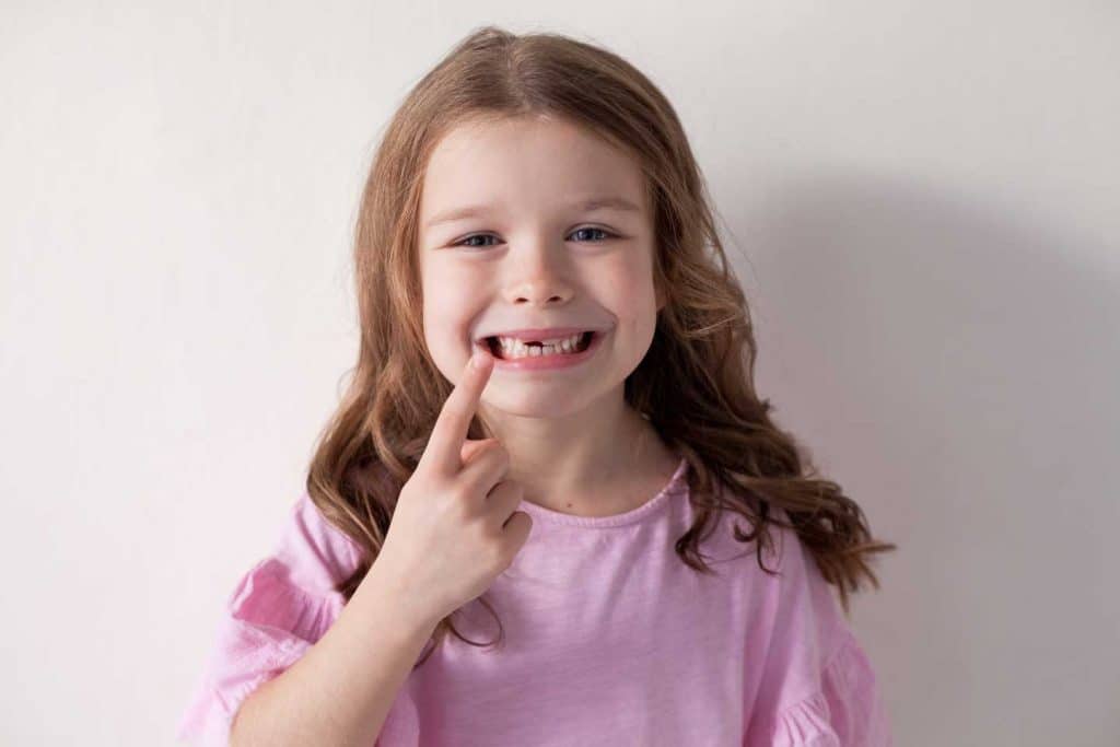 Beautiful little girl shows a fallen tooth