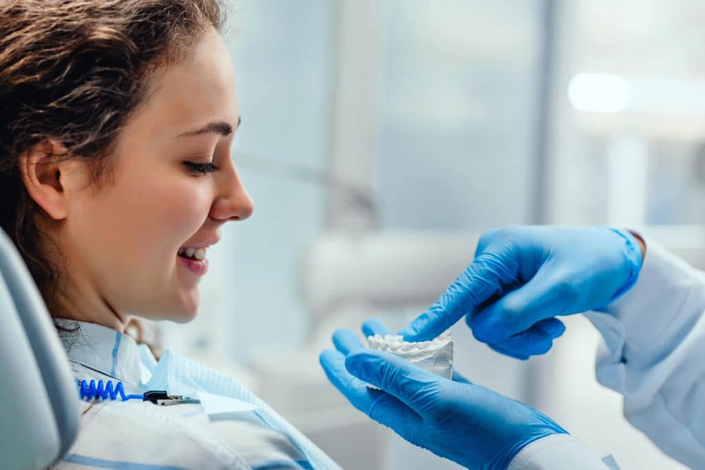 Dentist explaining his female patient about teeth care