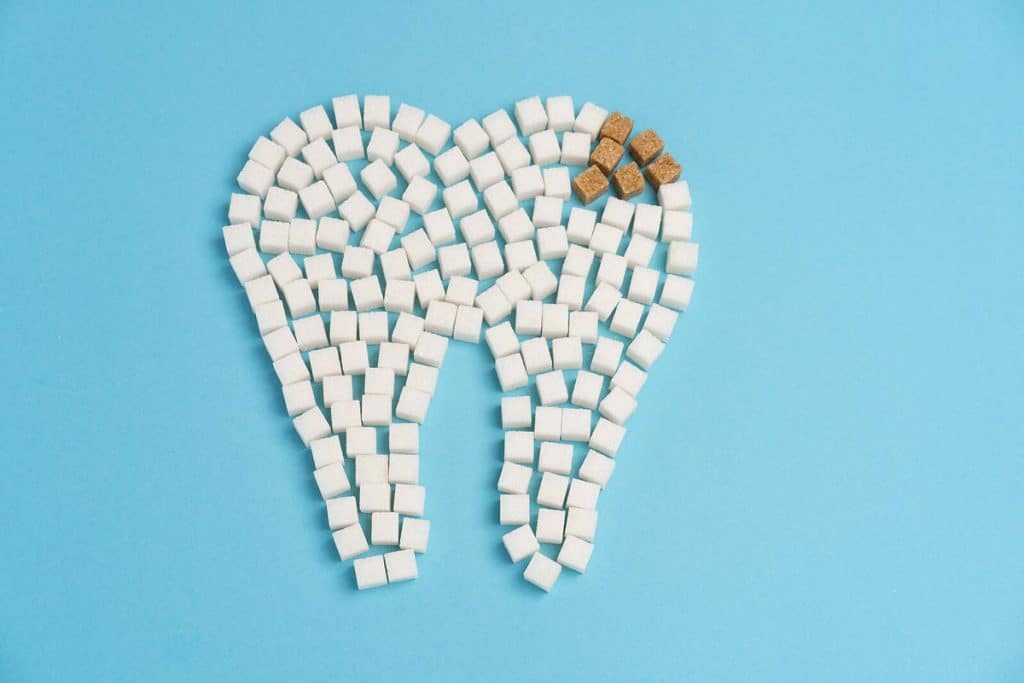 White Sugar cubes shape form tooth brown sugar caries blue background.|White Sugar cubes shape form tooth brown sugar caries blue background.|White Sugar cubes shape form tooth brown sugar caries blue background.|White Sugar cubes shape form tooth brown sugar caries blue background.