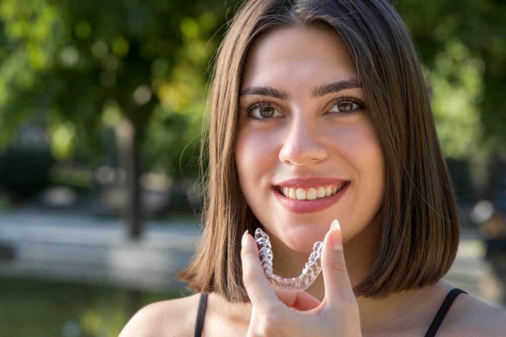 Invisalign bracer by Marsfield Dental Care|Beautiful smiling woman holding an Invisalign bracer