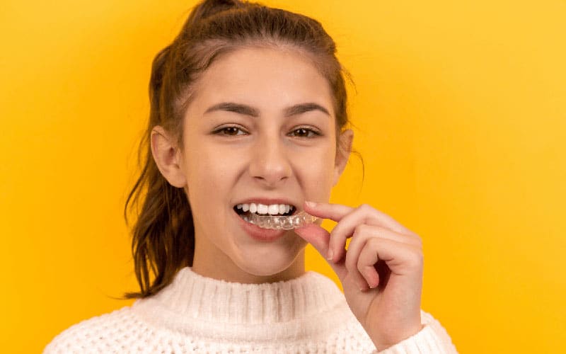 a girl holding teeth aligners|Dental Emergency: Tips from Your Local Dentist