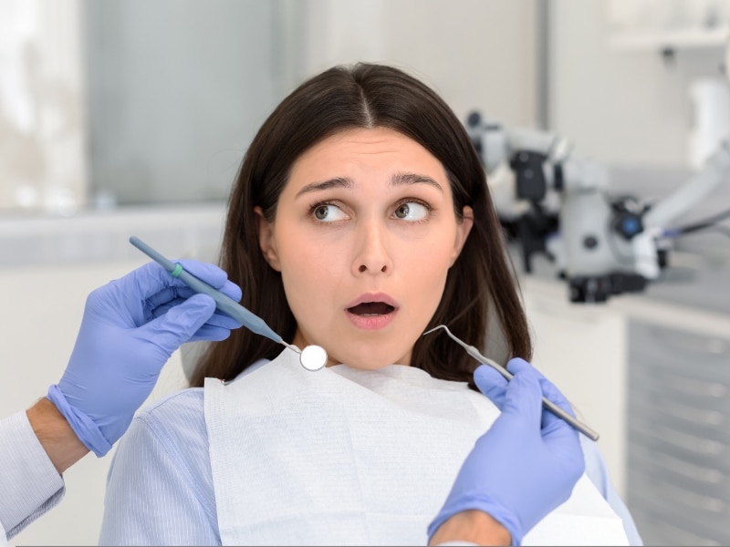 Nervous patient showing fear at the dentist’s office, a common sign of dental anxiety.