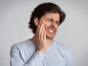 a man experiencing pain after ignoring wisdom tooth removal aftercare.